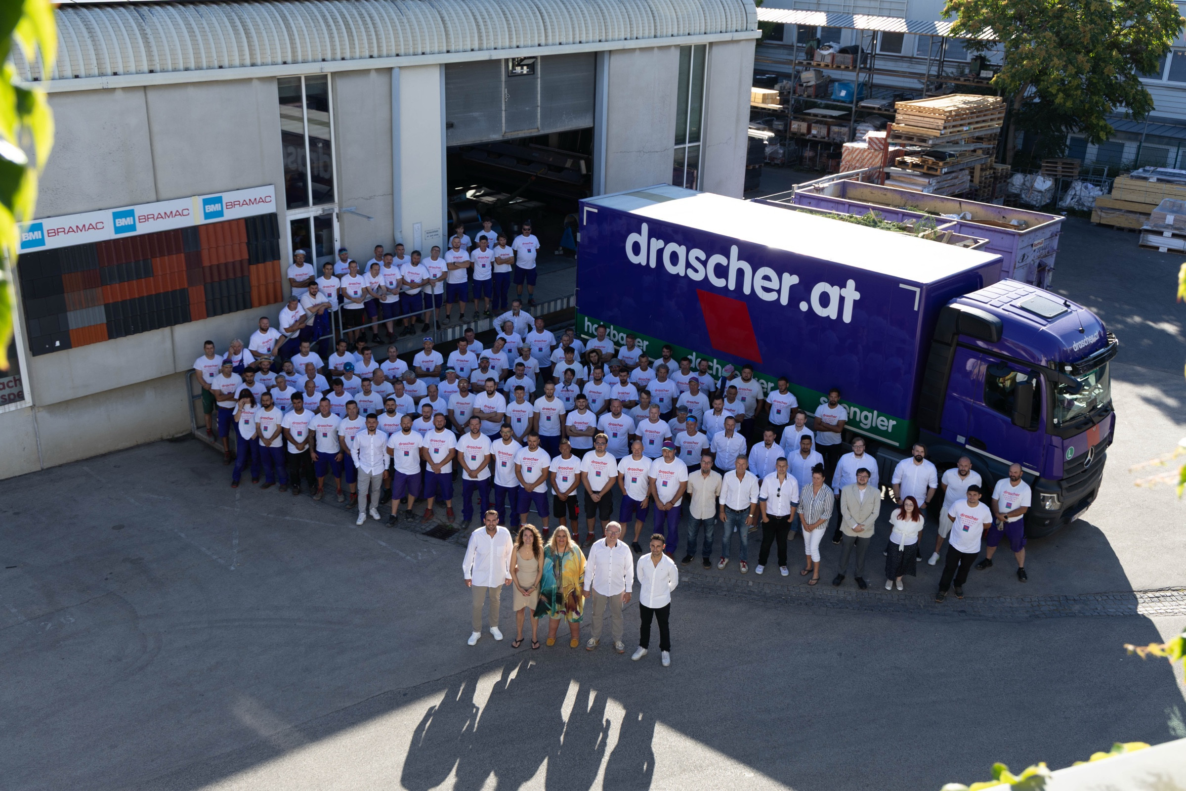 Das gesamte drascher-Team vor dem violetten Firmen-LKW am Betriebsgelände in Wien
